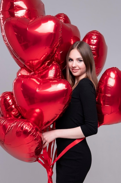 Chica sexy con una cara hermosa Modelo entre globos de gel en forma de corazón rojo