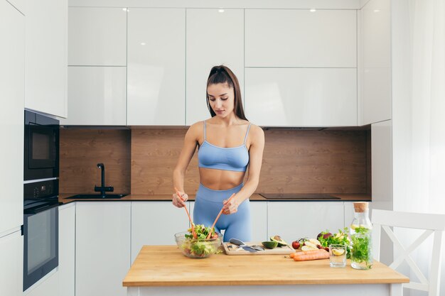 chica sexy, deportista prepara ensalada en casa