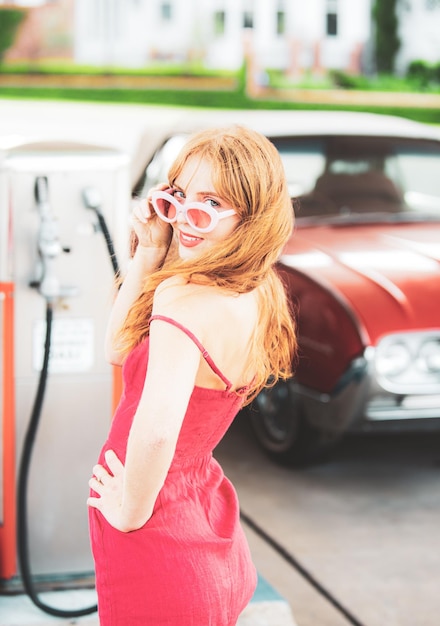 Chica sexy con vestido rojo en la gasolinera