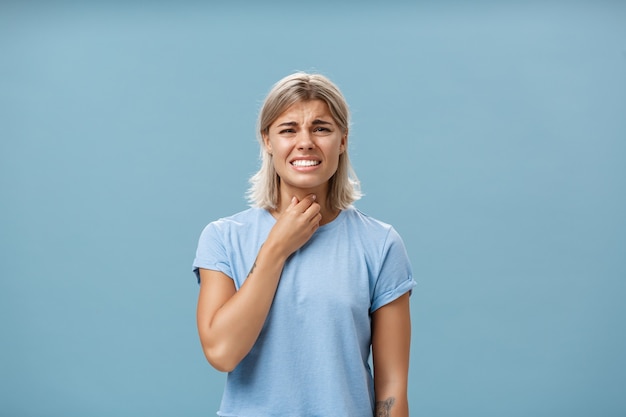 Chica siente malestar en la garganta resfriarse o tener alergia estacional tocando el cuello