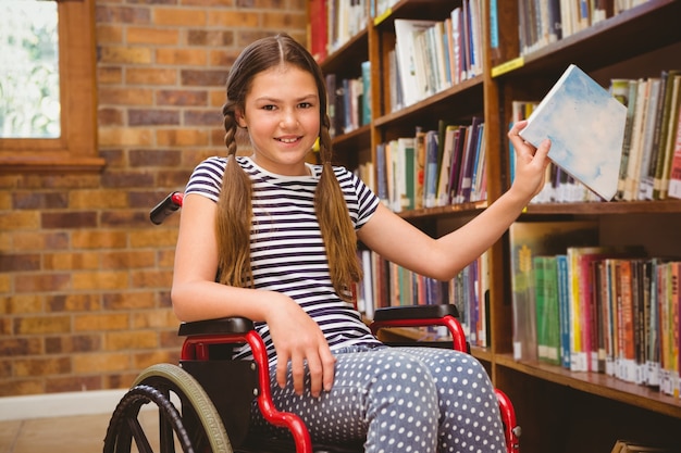 Foto chica en silla de ruedas que selecciona el libro en la biblioteca