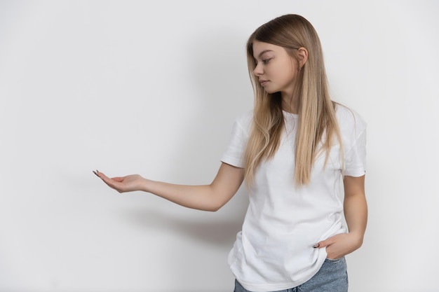 La chica se para sobre un fondo blanco con la mano extendida con espacio para tu texto o símbolo