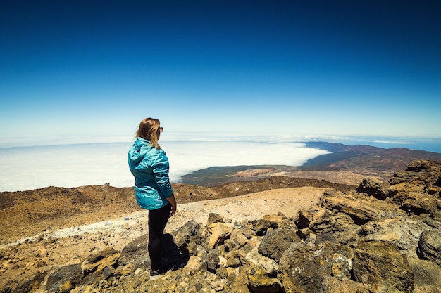 Chica sobre las nubes en la cima de la montaña por el volcán Teide Tenerife Islas Canarias España