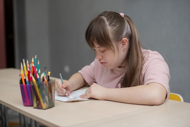 Chica soleada pintando en clase de arte en la escuela Día mundial de las personas con síndrome de down