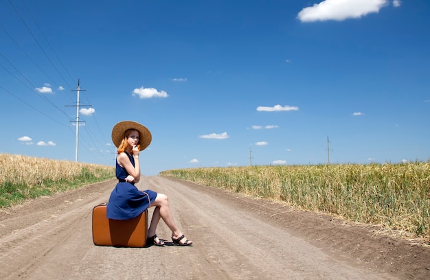 Chica solitaria con maleta en la carretera.