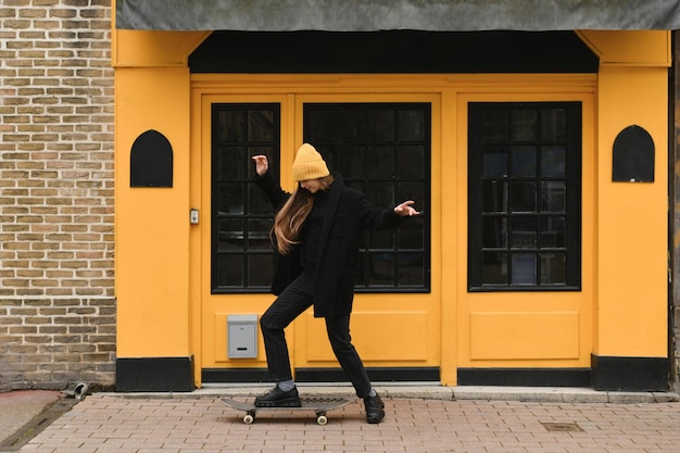 Chica con un sombrero amarillo con una patineta.