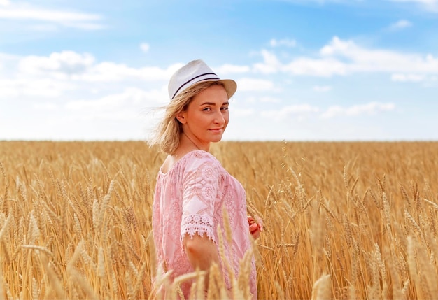 Una chica con sombrero en un campo de trigo, se regocija, disfruta de la vida, el verano, la naturaleza, la felicidad.