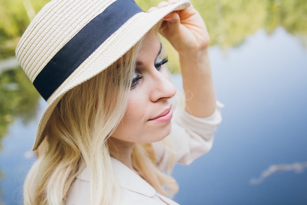 Chica con un sombrero descansando en el lago de otoño en el puente