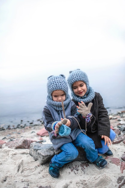 Chica con sombrero gris de punto compartiendo guantes con su hermano congelado