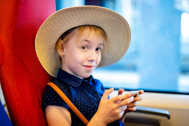 Chica del sombrero jugando con el teléfono móvil en el autobús