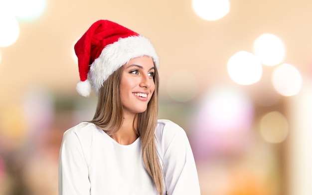 Chica con sombrero de navidad riendo sobre fondo desenfocado