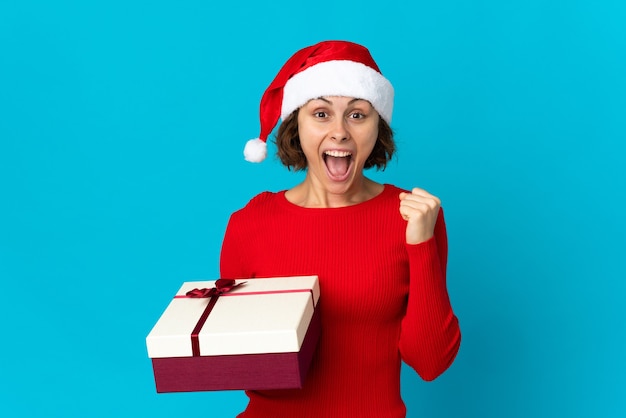 Chica con sombrero de Navidad sobre un fondo azul.