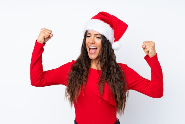 Chica con sombrero de Navidad sobre fondo blanco aislado celebrando una victoria