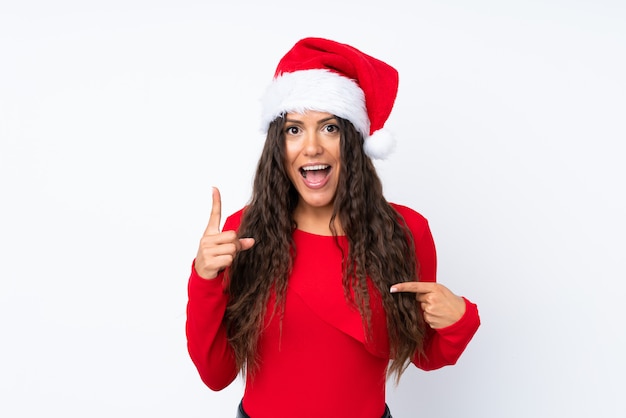 Chica con sombrero de Navidad sobre fondo blanco aislado con expresión facial sorpresa