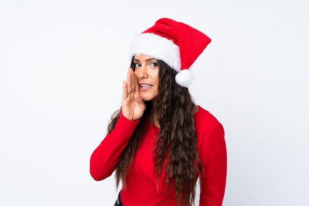 Chica con sombrero de Navidad sobre fondo blanco aislado susurrando algo