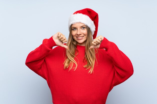 Chica con sombrero de Navidad sobre pared azul aislada orgullosa y satisfecha