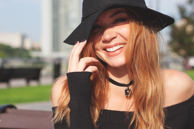 Una chica con un sombrero negro camina por la ciudad.