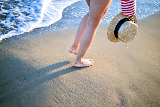 chica con sombrero de paja camina por el mar