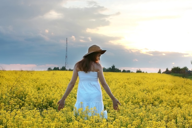 Foto chica con sombrero de paja en campo de flores amarillas en flor