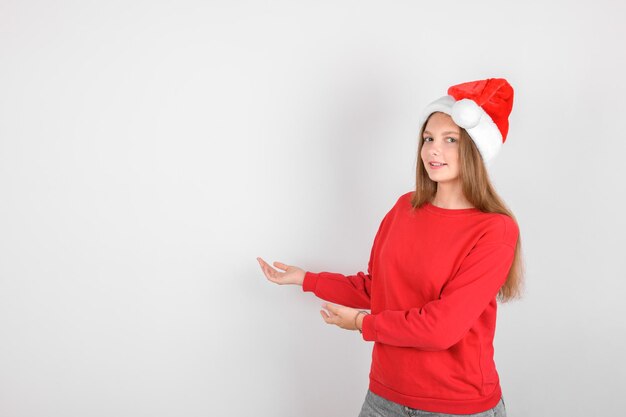 Una chica con sombrero de Papá Noel con capucha roja hace un gesto que muestra la venta de Navidad