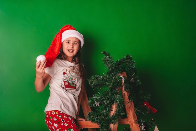 Chica con un sombrero de Papá Noel se está divirtiendo sobre un fondo verde el concepto de espacio de Navidad para texto