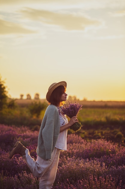 Chica con sombrero recoge una cosecha de lavanda puesta de sol en el campo puesta de sol recogiendo lavanda