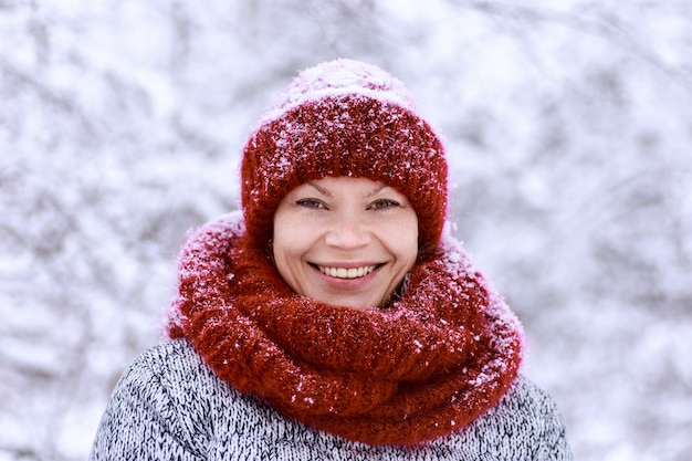 Chica del sombrero rojo y una bufanda divirtiéndose en el parque de invierno.