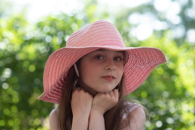 Chica con sombrero rosa y vestido blanco. Niña de 9 años en el verano en el jardín.