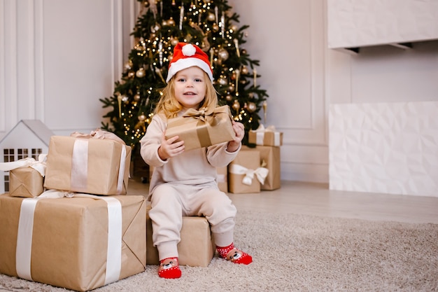 Chica con sombrero de Santa con regalo de Navidad sobre fondo de árbol de Navidad.