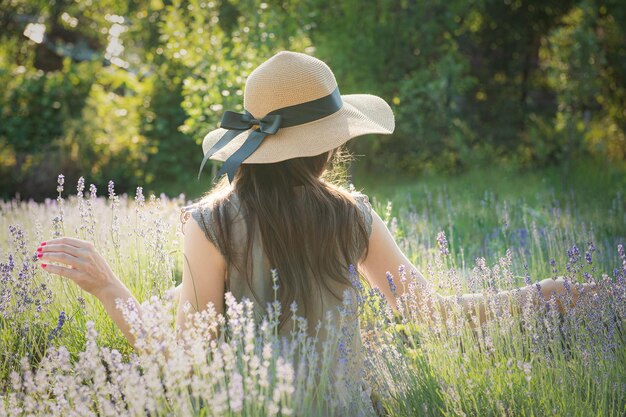 La chica del sombrero se sienta en medio de un campo de lavanda.