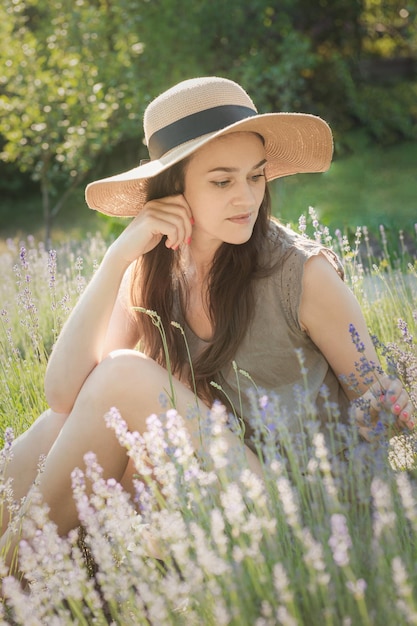 La chica del sombrero se sienta en medio de un campo de lavanda.