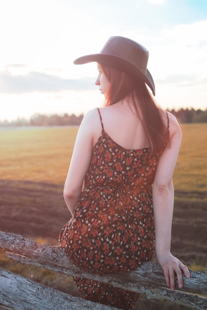 Chica con sombrero de vaquero en la cerca