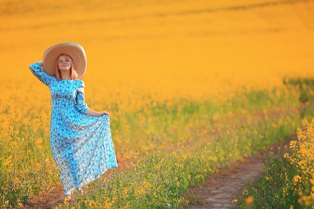 Chica en un sombrero de vestido largo vintage en un campo de flores, feliz verano soleado libertad mujer