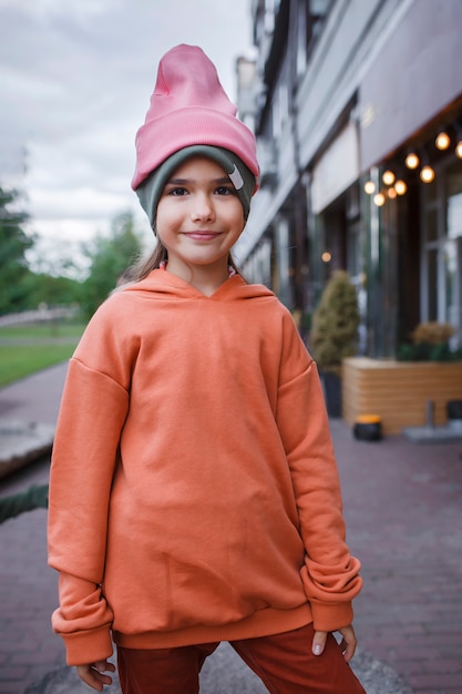 Chica con sombreros de moda y sudadera con capucha divirtiéndose en el parque otoño vibraciones otoño estilo de belleza moda infantil