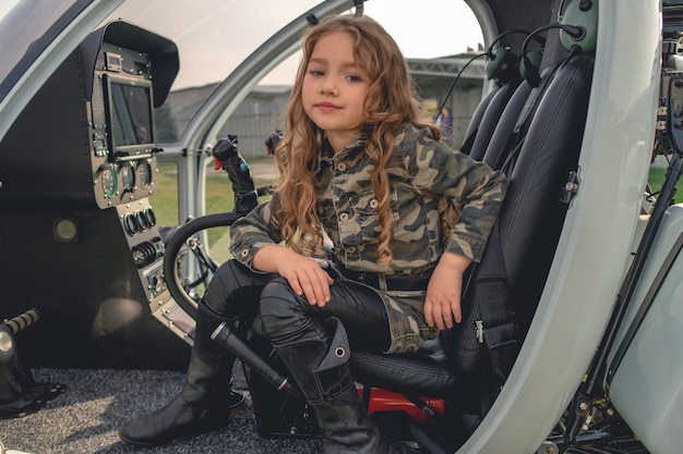 Chica entre soñadora sentada en cabina abierta de helicóptero