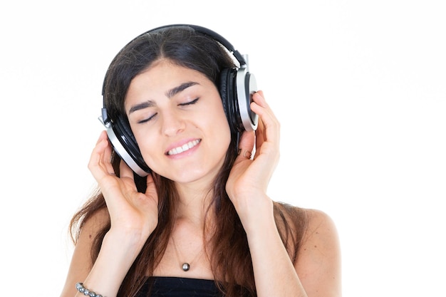 Chica soñando mujer bonita con auriculares disfrutando de la música aislado sobre fondo blanco.