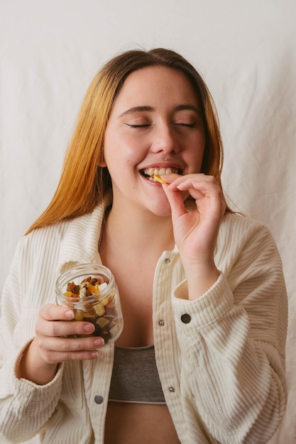 Chica sonriendo mientras muerde un bocadillo saludable