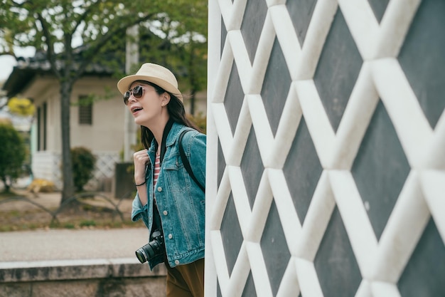 Chica sonriente cabeza pop caminando por pared rómbica