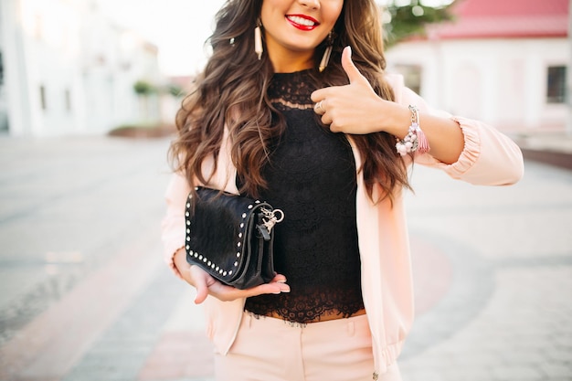 Chica sonriente demostrando el bolso con el pulgar hacia arriba.