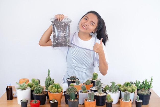 Chica sonriente feliz con tierra para macetas para cactus