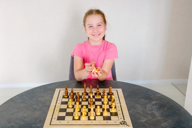 chica sonriente en la mesa con piezas de ajedrez en sus manos