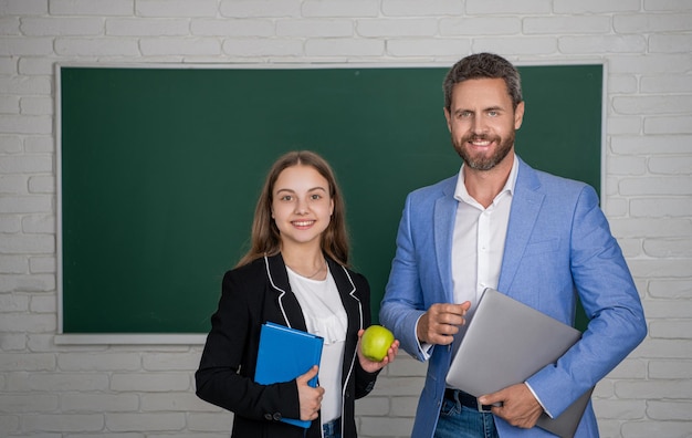 Chica sonriente con profesor de hombre en la educación en el aula