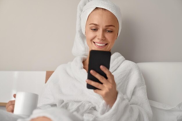 Chica sonriente con smartphone en la cama