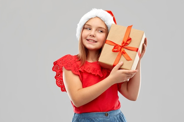 Foto chica sonriente con sombrero de snata con regalo de navidad