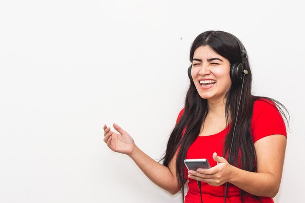 Chica sonriente con su teléfono en la mano y usando grandes auriculares