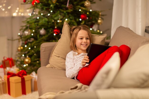 chica sonriente con una tableta PC en la casa de Navidad