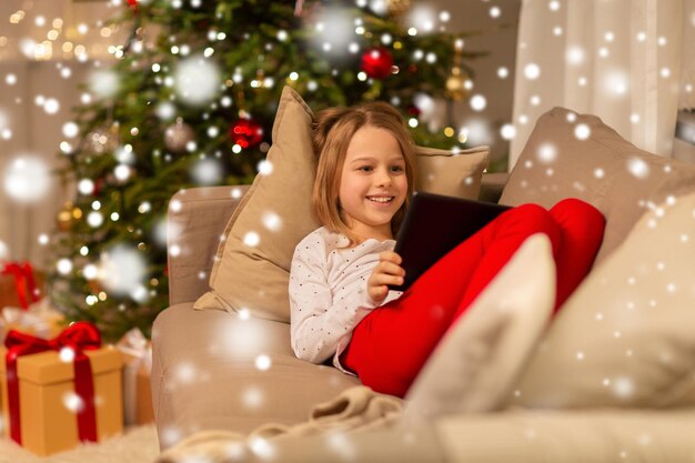 chica sonriente con una tableta PC en la casa de Navidad