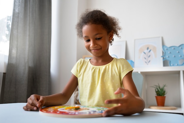 Foto chica sonriente de tiro medio haciendo rompecabezas en la mesa