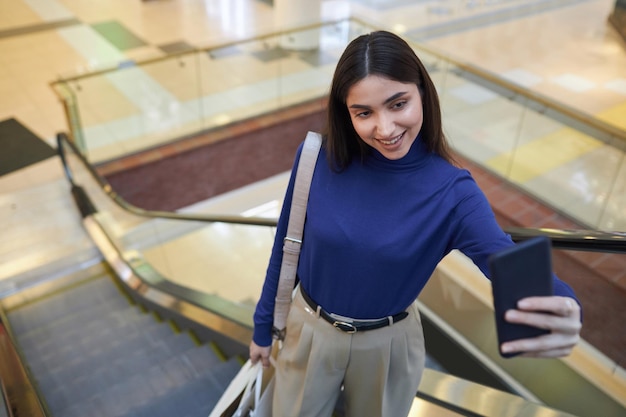 Una chica sonriente tomando una selfie en el centro comercial.