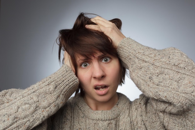 Chica sorprendida agarra su cabello pensando en algo Oportunidades perdidas debido a la mala memoria